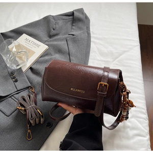 Detail of vintage brown leather bag with golden logo and decorative wooden beads strap