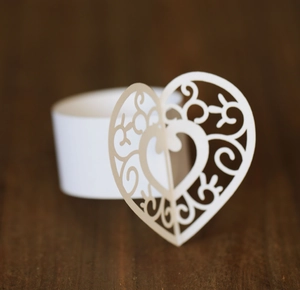 Macro shot of white laser-cut paper napkin ring with intricate hollow heart pattern
