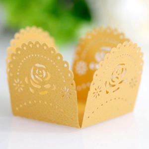 Detail of laser-cut golden rose pattern cupcake wrappers for elegant party decoration