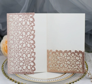 Detail of rose gold glitter laser cut wedding invitation card with intricate floral patterns