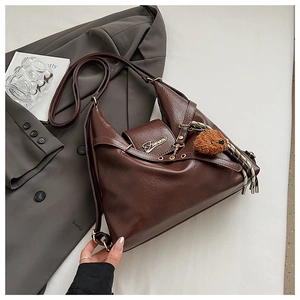 Détail du sac cabas en cuir texturé avec logo doré et breloque ours en peluche
