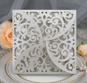Macro detail of laser cut floral pattern on pearl white wedding invitation cover