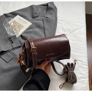 Detail of vintage brown leather bag with dual straps and antique gold hardware accent