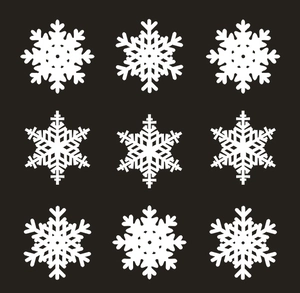 Close-up of laser-cut white snowflake decorative card designs in nine geometric patterns