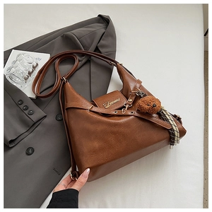 Détail d'un sac cabas vintage marron avec breloque ours et accessoire à franges rayées