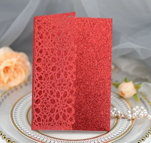 Macro shot of glitter red laser-cut lace wedding invitation on a decorative plate