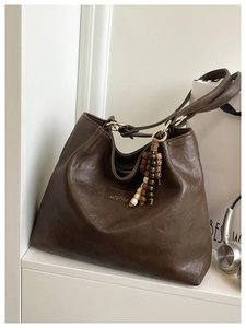 Deep brown vintage Hobo bag featuring a unique wooden beaded tassel and metal ring hardware