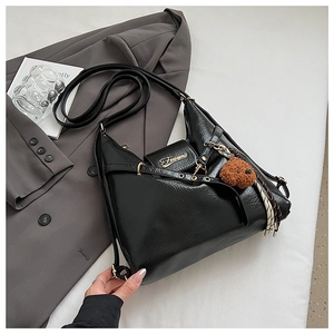 Détail d'un sac cabas noir en simili cuir brillant avec logo en métal et breloque ours