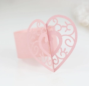 Détail d'un rond de serviette cœur rose découpé au laser avec motif floral pour mariages