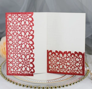 Detail of red glitter laser-cut invitation with floral patterns on a ceramic plate