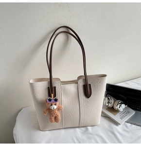 Cream tote bag with brown straps featuring a cute plush bear charm for daily commute