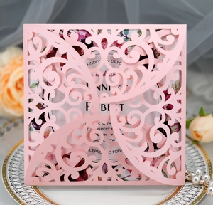 Close-up of pink laser-cut floral wedding invitation with elegant pearlescent paper texture