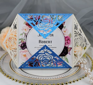 Detail of laser-cut rose invitation card with blue glitter inlay on ceramic plate