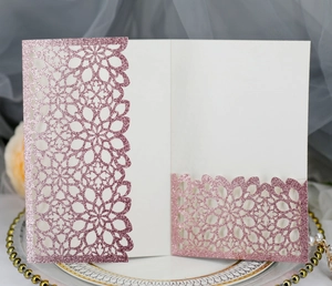 Detailed laser-cut glitter wedding invitation with pink floral hollow design on a tray