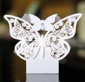Detail of white laser-cut butterfly candy box with pearlescent finish and ribbon