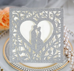 Détail de l'invitation de mariage pailletée argent avec cœur découpé et silhouette de couple