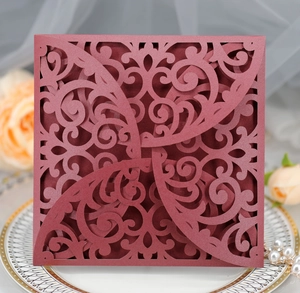 Macro detail of wine red laser cut wedding invitation with elegant floral hollow patterns