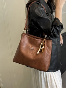 Vintage brown faux leather tote bag with wooden bead tassel and metal logo detail