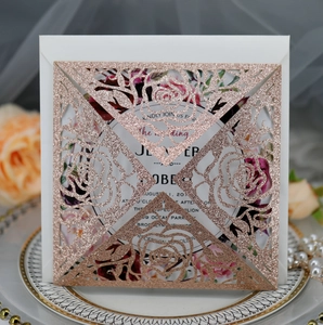 Macro detail of laser-cut rose gold glitter wedding invitation with floral printed insert