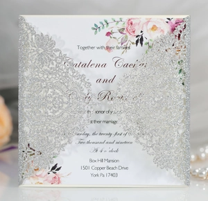 Detail of silver laser-cut wedding invitation with floral insert and elegant glitters
