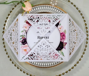 Detail showing white laser-cut lace wedding invitation with floral inner card and Robert name