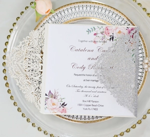 Laser-cut wedding invitation detail with white glitter lace and floral inner card