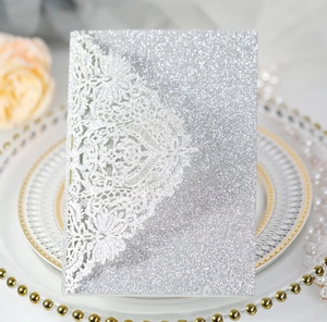 Détail d'un faire-part de mariage pailleté argenté avec motifs de dentelle découpés au laser