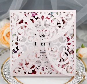 Detail of laser-cut hollow rose wedding invitation with elegant floral lace and pink cover