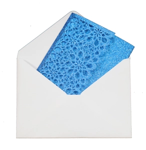 Close-up of laser-cut blue glitter invitation card with floral hollow pattern and white envelope