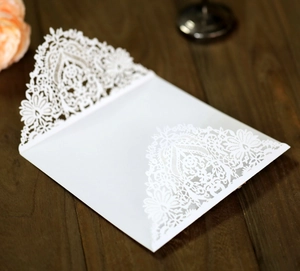 Close-up of laser-cut white lace floral patterns on elegant kraft wedding invitations