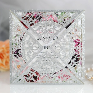 Macro shot of silver glitter lace laser-cut wedding invitation with floral insert