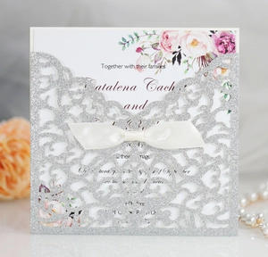 Dettaglio dell'invito glitter argento tagliato a laser con inserto floreale e fiocco