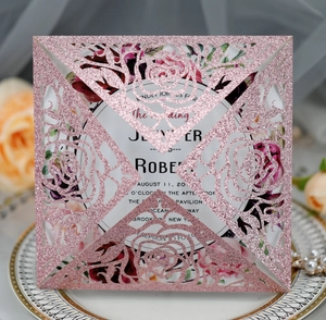 Detail of pink glitter laser-cut rose wedding invitation on decorative porcelain plate