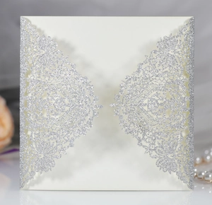 Detail of glitter silver laser-cut lace pattern on an elegant ivory wedding invitation