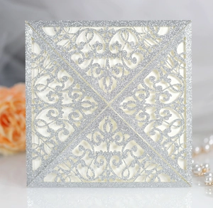 Detailed close-up of silver glitter laser-cut invitation with intricate floral lace patterns
