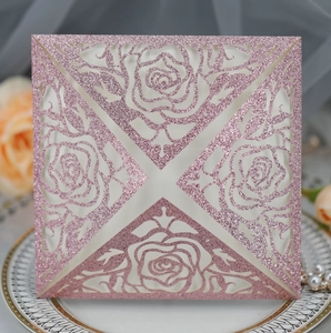 Detail of pink glitter laser-cut wedding invitation featuring intricate rose patterns