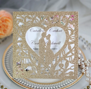 Gros plan d'une invitation de mariage dorée à paillettes découpée au laser avec cœur