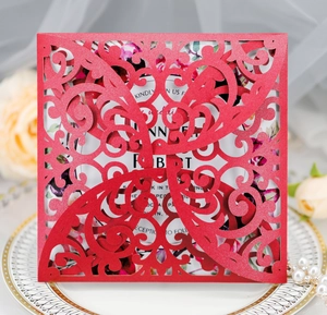 Elegant laser-cut red wedding invitation card with floral hollow design on a white plate