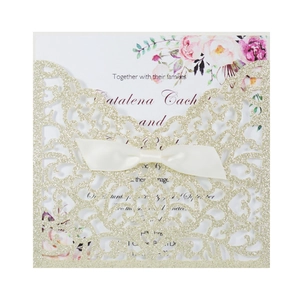 Dettaglio dell'invito di nozze glitter oro champagne con fiocco di seta e inserto floreale
