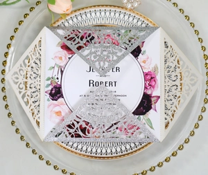 Macro view of silver glitter laser-cut invitation with floral card on a decorative plate