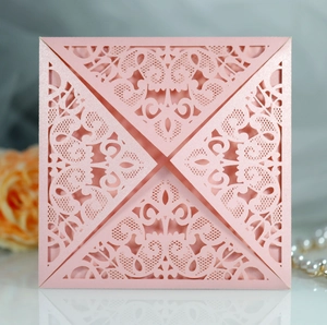 Macro shot of pink laser-cut lace wedding invitation with elegant floral hollow patterns