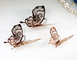 Close-up of rose gold hollow-out lace butterfly stickers with detailed metal texture