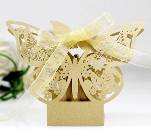 Detail of laser-cut golden butterfly candy box with hollow patterns and yellow ribbon