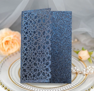 Detail of dark blue glitter wedding card featuring intricate laser cut floral patterns