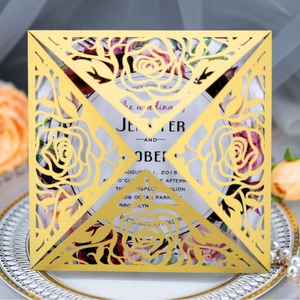 Elegant gold laser-cut rose wedding invitation set with floral card on a white tray