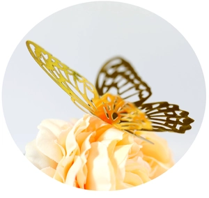 Macro detail of 3D metallic gold butterfly with hollowed geometric patterns on pink flowers