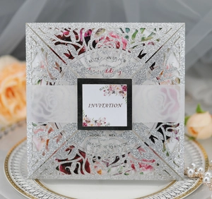 Close-up of laser-cut silver glitter wedding invitation with floral hollow design