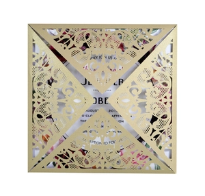 Close-up of laser-cut lace pattern on gold square wedding invitation with floral card