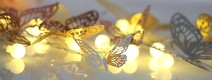 Detailed macro view of laser-cut butterfly LED string lights with warm glowing orbs