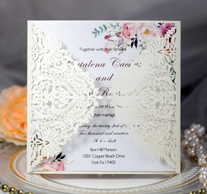 Macro view of laser-cut lace wedding invitation with floral insert and kraft paper detail